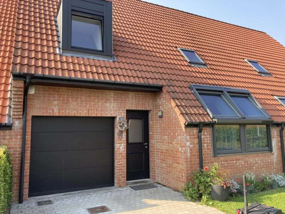 Toiture en tuiles rénovée avec fenêtres de toit Velux et porte de garage anthracite